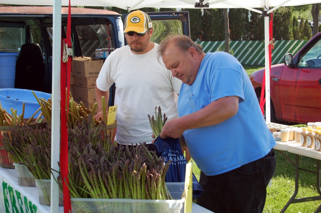 A customer makes a selection of some asparagus as vendor Mike Toboyek (right) looks on. Toboyek of Riverwood Produce Farm had asparagus, rhubarb, honey and other products available at his stand.