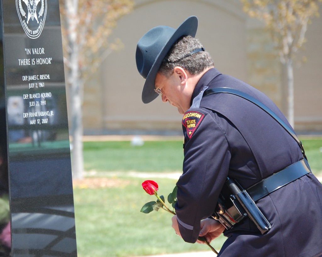 A state trooper lays a flower at the Kenosha Public Safety Mounument at the reading of the name of slain sheriff's Deputy Frank J. Fabiano Jr.