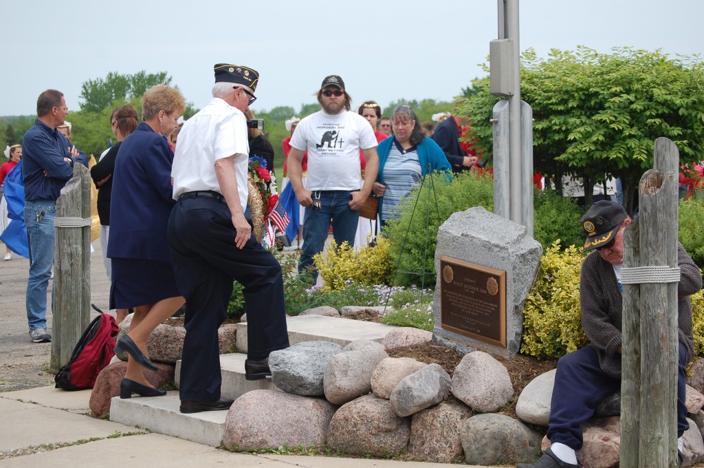 Joanne Maiter, Legion Auxiliary, and American Legion Post 544 Chaplain George Reehoff place a reef at the flagpole outside the legion hall in Legion Park.