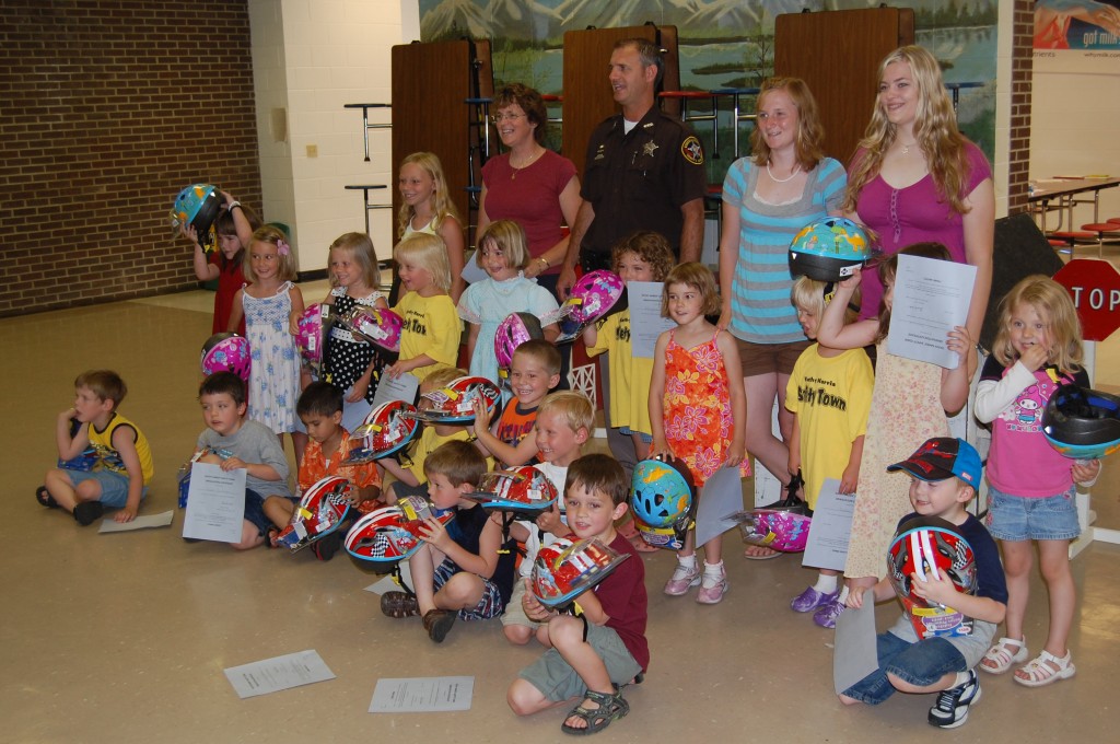 The Karen Harris Safety Town class of 2009 poses for a group photo with the instructors and Deputy Friendly, also known as Deputy Ray Rowe. They are displaying the bike helmets they received on the last day of class.