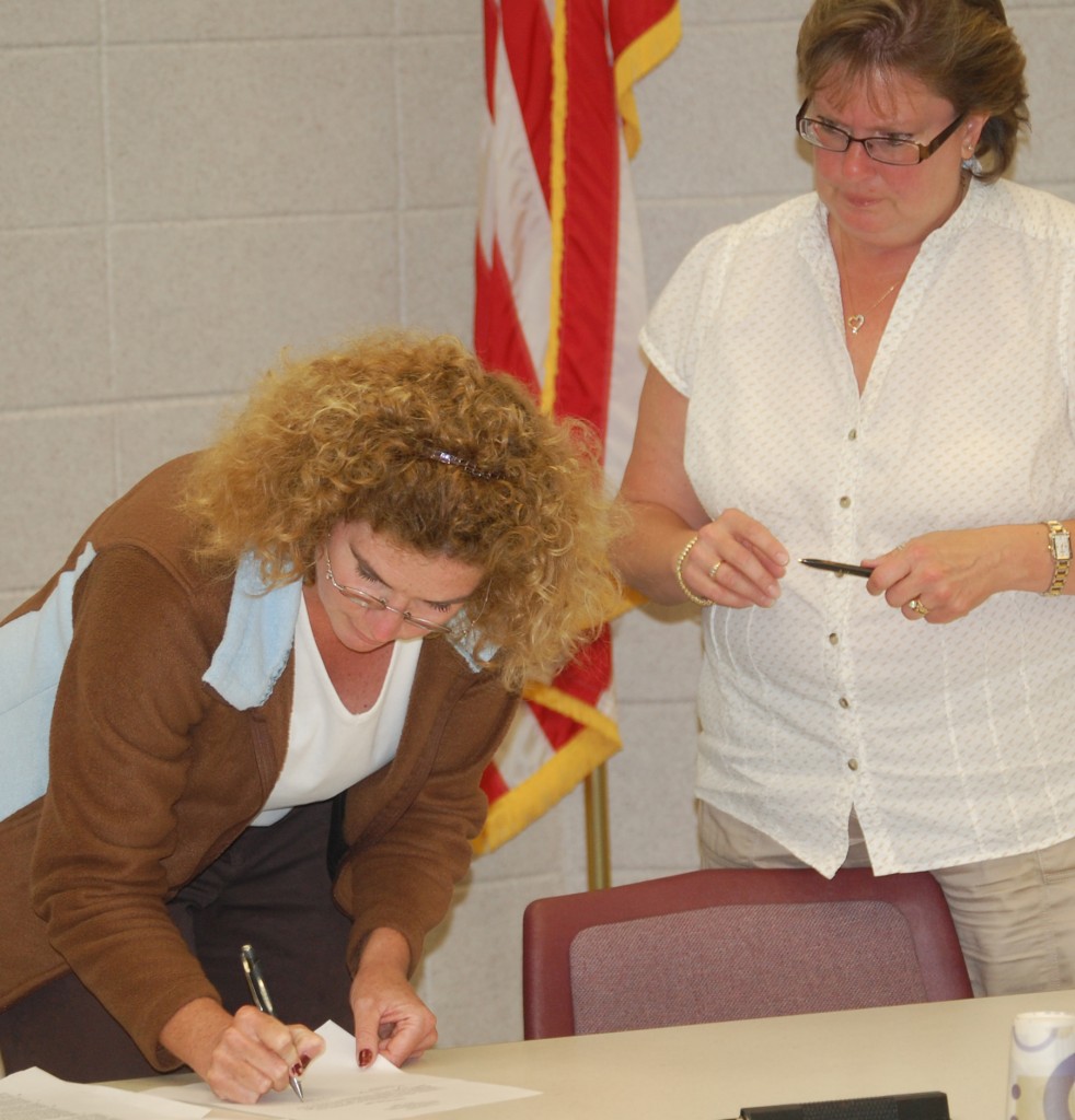 New Salem School Board member Lisa Hinze (right) signs her oath of office as board Clerk Peggy Aull looks on