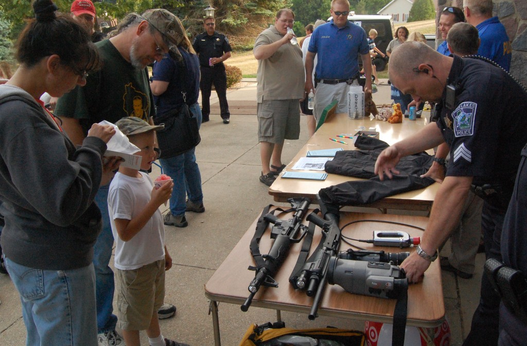 Twin Lakes police Sgt. Tim Shuda asks youngster Shane Davis which piece of equipment Shane thinks he uses the most, while Chuck Davis and Brenda Bischel look on. The right answer wasn't any of the impressive firearms on the table or even Shuda's handgun but his pen and his radio.