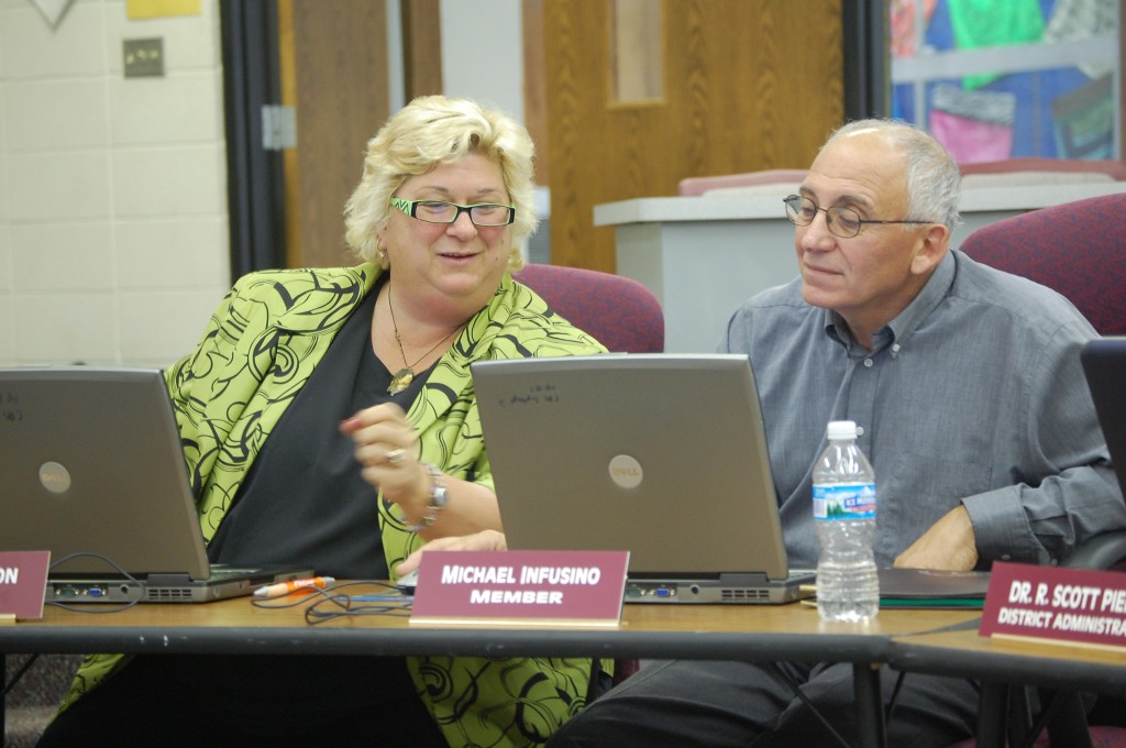 Central High School Board member Mary Anderson (left) shows board member Michael Infusino how to access materials attached to agenda items at Tuesday's School Board meeting. The board used laptops for agenda materials instead of paper for the first time Tuesday night.