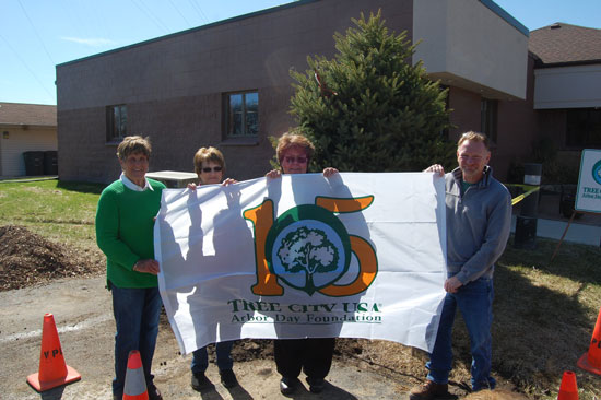 (From left) Village Trustees Barbara Brenner, Gloria Walter, Kathy Christensen and village President Terry Burns display the village's new 15-year Tree City USA flag.