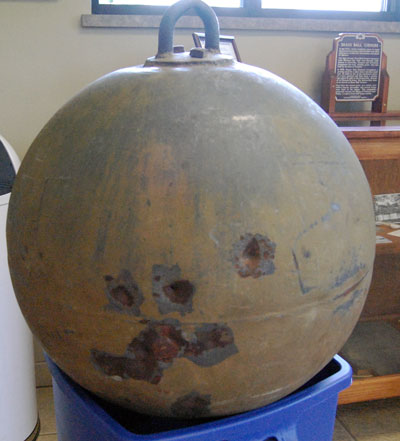 The donated brass ball. The origin of the dents is not known for sure. Some feel they might be from bullets fired at teh ball when it was performing its first duty as a mine buoy. Other think they were made when local folks took a few shots at the landmark as a lark.